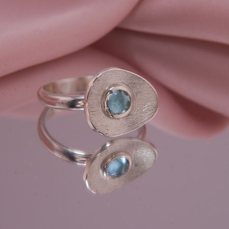 Frontansicht auf den Designerring Isola aus 925 Silber mit rundem Blautopas Swiss Blue und diamantierter Vertiefung.